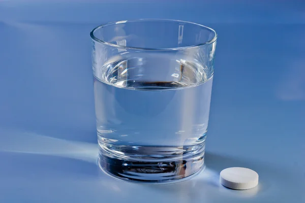 Glass of water with pill