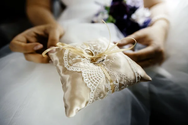 Wedding rings for the newlyweds in the hands on silk pillow