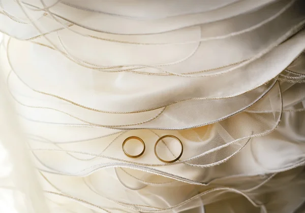 Gold wedding rings on wedding dress