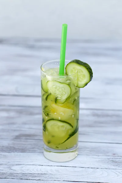 Cucumber Water in a glass with straws on wood background