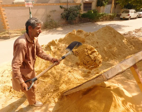 Old Man Is Refining Sand By His Shovel.