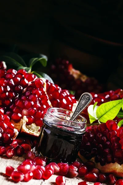 Homemade pomegranate jam in a glass jar with a spoon