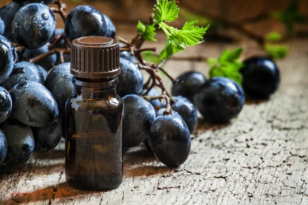Grape seed oil in brown bottle, bunch of grapes
