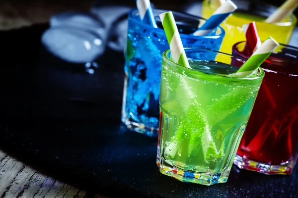 Colorful cocktails with straws on a dark background