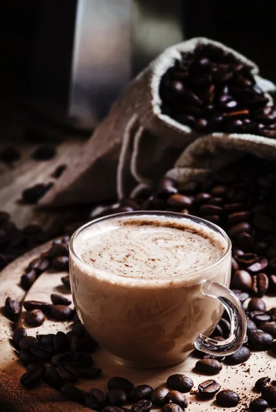 Coffee with milk, coffee maker, coffee beans, dark toned image