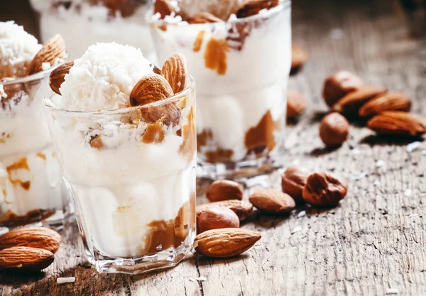 Ice cream with peanut sauce, hazelnuts and almonds in glasses