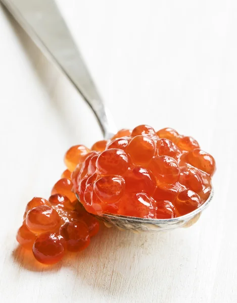 Red caviar in the silver spoon on a white background