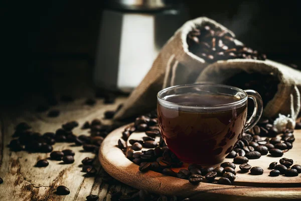 Black coffee in a cup on a background of coffee bags with a coffe maker