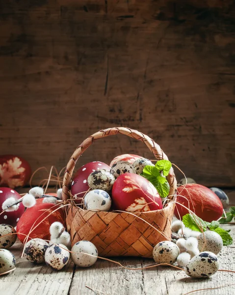 Painted eggs and speckled quail eggs in a wicker basket