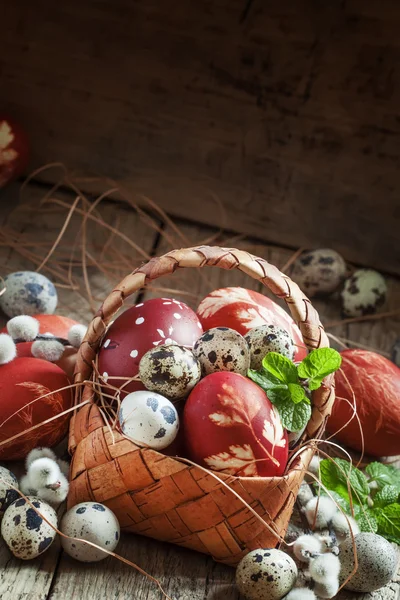 Painted eggs and speckled quail eggs in a wicker basket