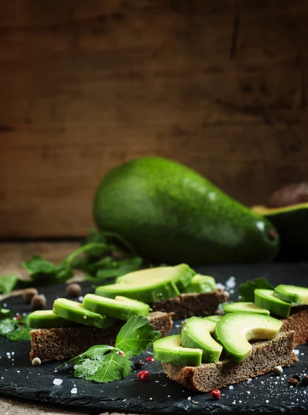 Sandwiches with avocado, black rye bread and spices