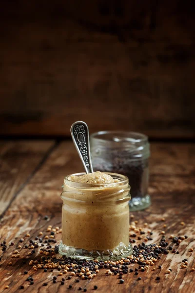 Mustard in a glass jar and seeds black and yellow