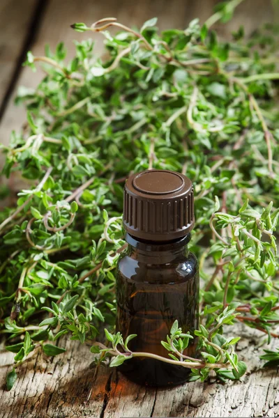 Essential oil of thyme in a bottle and fresh herb thyme