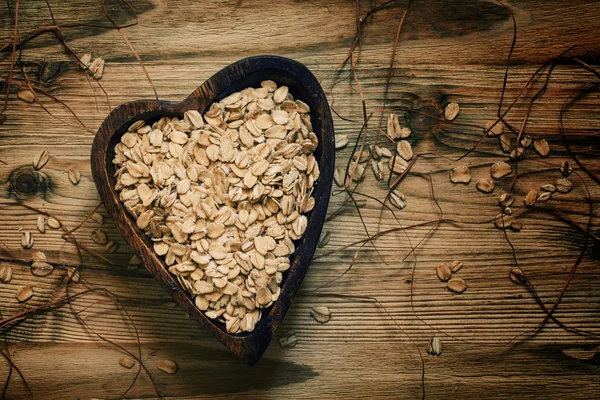 Oat flakes in a wooden bowl in the shape of a heart