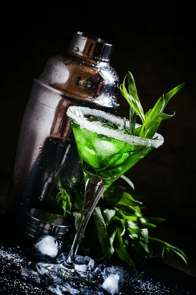 Green cocktail with tarragon and ice in martini glass