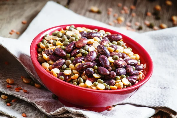 Bean mix: purple beans, green and red lentils, dry peas in a red bowl