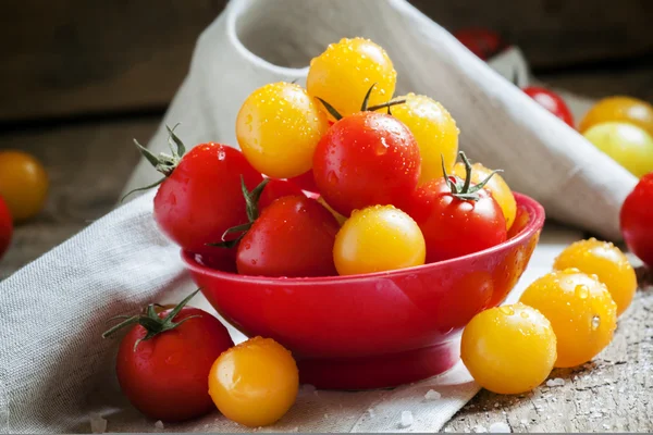 Red and orange cherry tomatoes in a red bowl