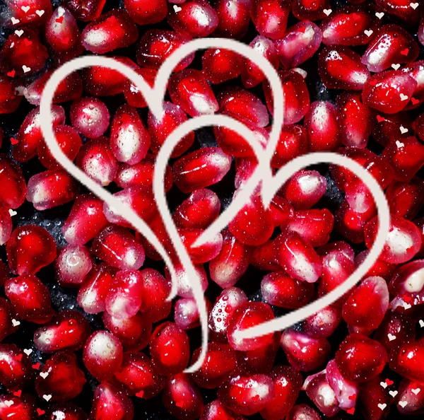 Composition for Valentine\'s Day with pomegranate seeds and painted hearts