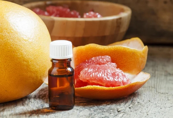 Grapefruit essential oil in a small bottle and fresh grapefruit