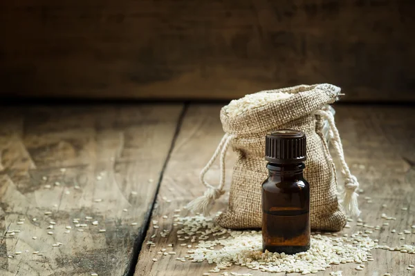 Essential sesame oil in a bottle of brown glass and sesame seeds