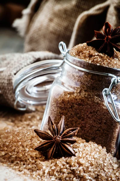 Brown cane sugar in bags made of burlap and a glass jar with a star anise