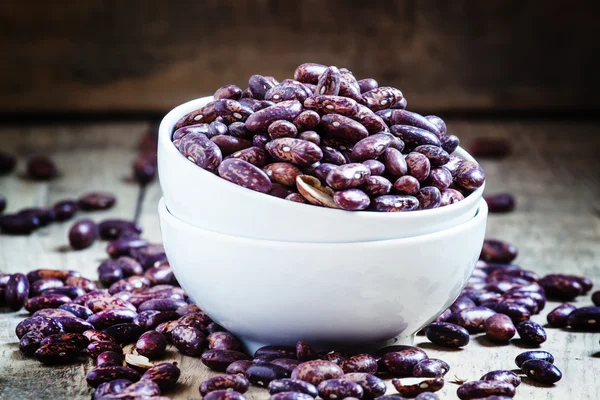 Purple-brown dry beans in a white porcelain bowl