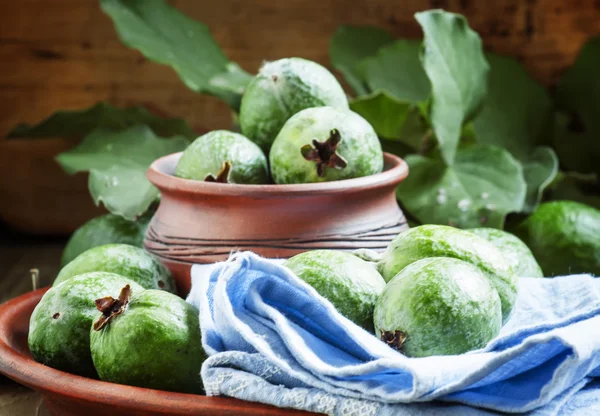 Fresh green feijoa fruits in clay bowl with blue napkin