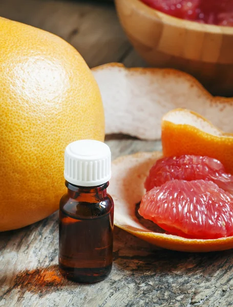 Grapefruit essential oil in a small bottle and fresh grapefruit