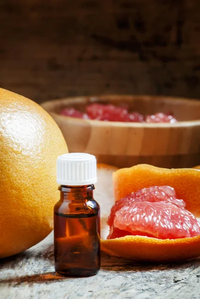 Grapefruit essential oil in a small bottle and fresh grapefruit