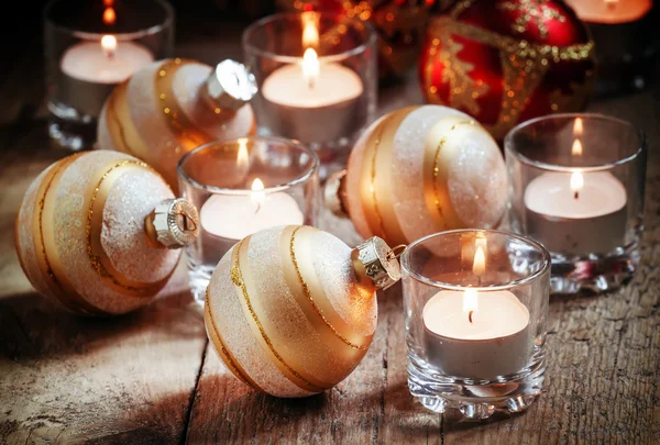 Christmas balls, burning candles on the old wooden background