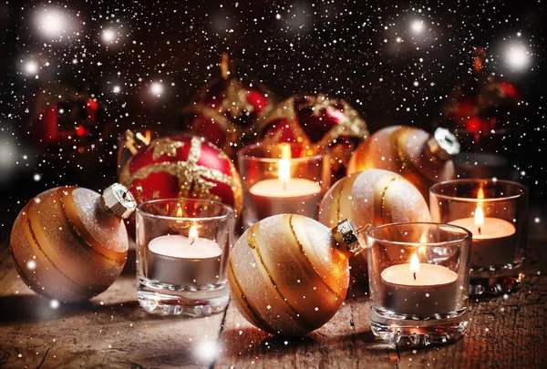 Christmas balls, burning candles on the old wooden background