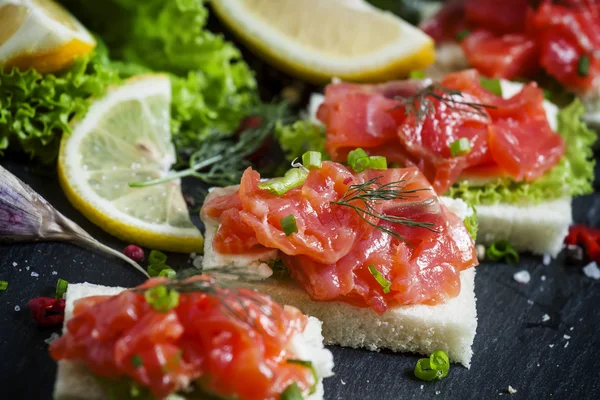 Small sandwiches with salty salmon,  soft cheese and green salad