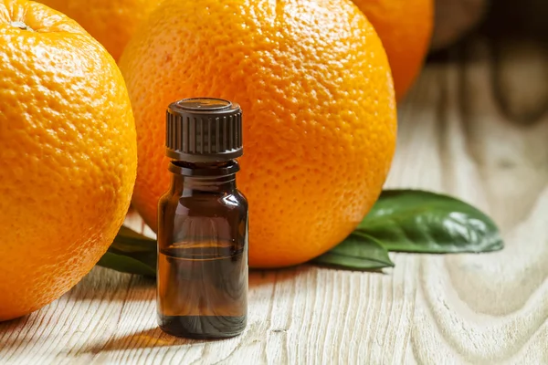 Orange oil in a small bottle and fresh fruits