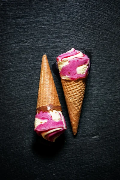 Strawberry and vanilla ice cream in a waffle cone