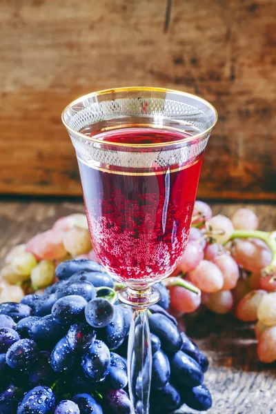 Red sparkling wine in the glass, blue and pink grapes