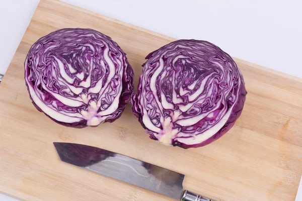 Red leaved cabbage cut in half on chopping board