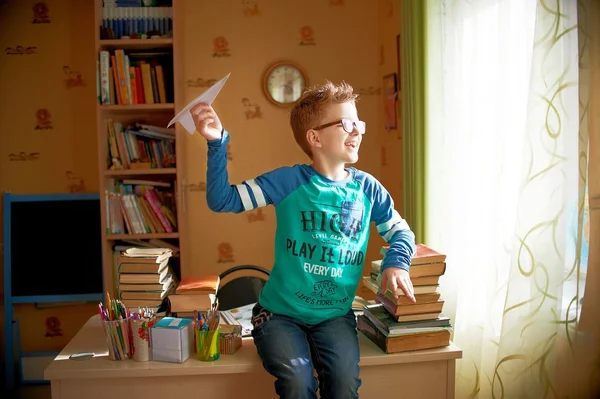 Boy with origami toy plane at home