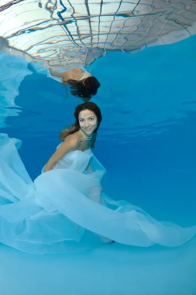 Young beautiful woman with long hair in a long white dress under