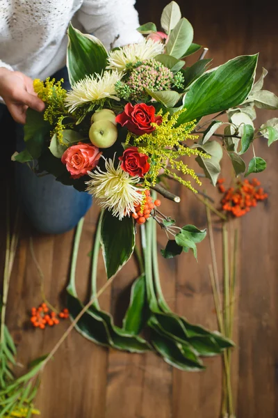 Florist make a bouquet of flowers and branches