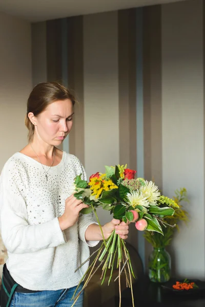 Florist make a bouquet of flowers and branches