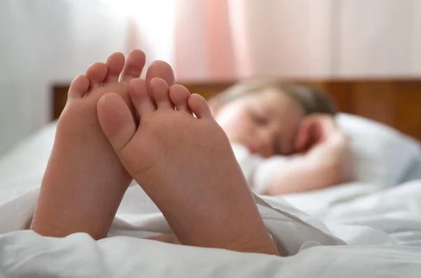 Little girl\'s feet who sleeps inher bed closeup