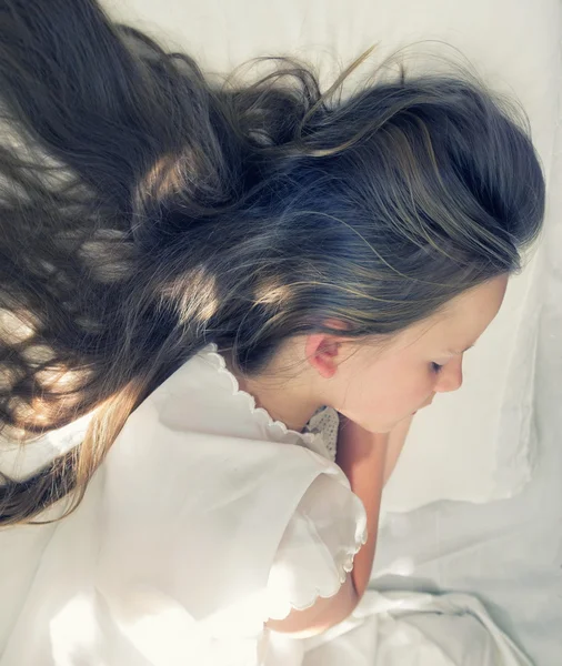 Little girl is sleeping and her long hair spreads on pillow
