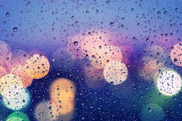Drops of rain on window with abstract bokeh background