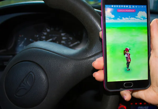 Dnipropetrovsk, Ukraine - July 23, 2016: The female hand holding phone with game Pokemon GO in the car