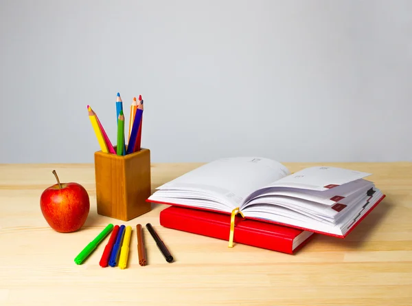 Back to school background with books, pencils and apple over wooden table