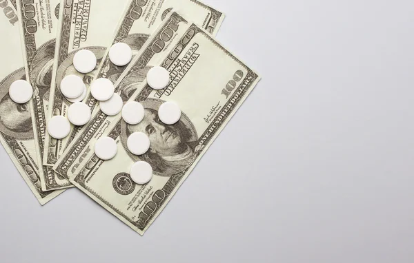 White pills and money, health expense concept,  care cost,