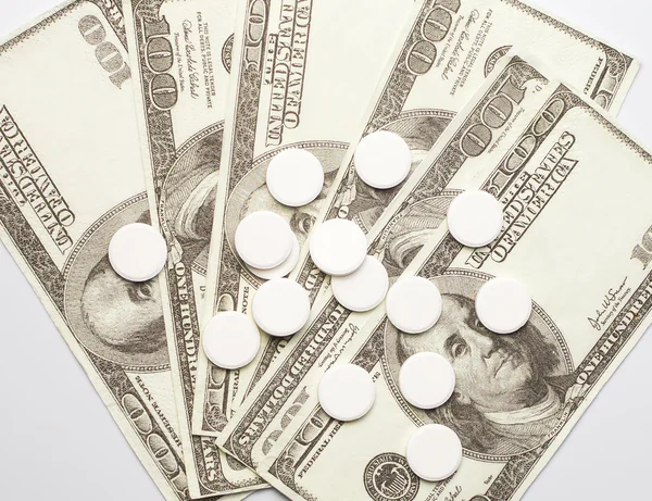White pills and money, health expense concept, care cost,