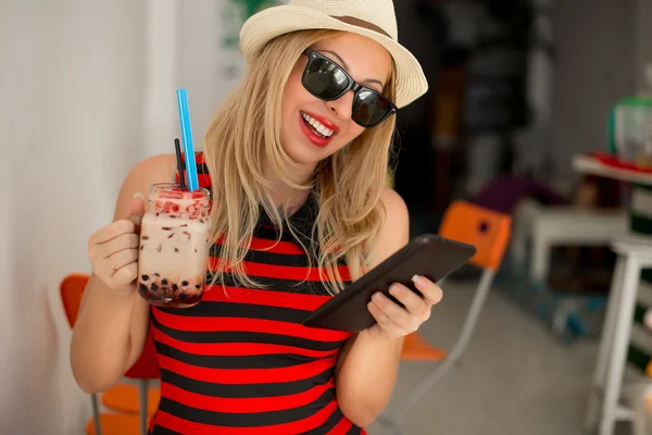 Happy young woman drinking coffee and using tablet computer. Woman reading electronic book on her digital tablet, browsing website pages on touch pad while breakfast in coffee shop