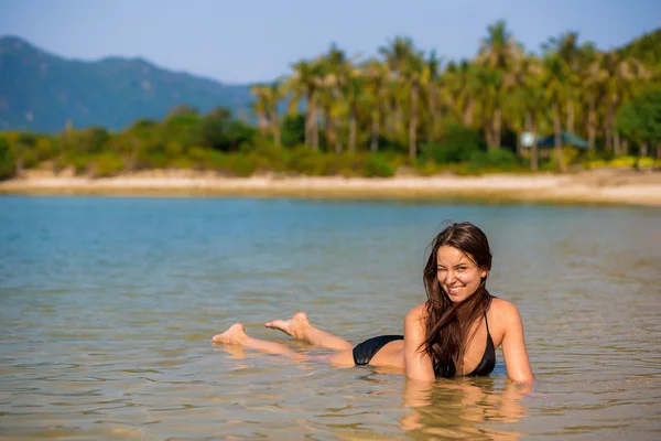 Cheerful, happy, successful Brunette girl. Woman smiling on vacation and enjoying the beautiful scenery. Slim sexy girl in a bikini swims in the ocean. in the ocean.