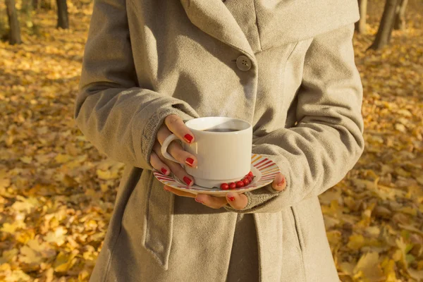 Female holding a cup of black coffee in the woods